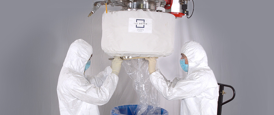 Two biomanufacturing professionals wearing protective equipment set up a continuous liner to transfer powder