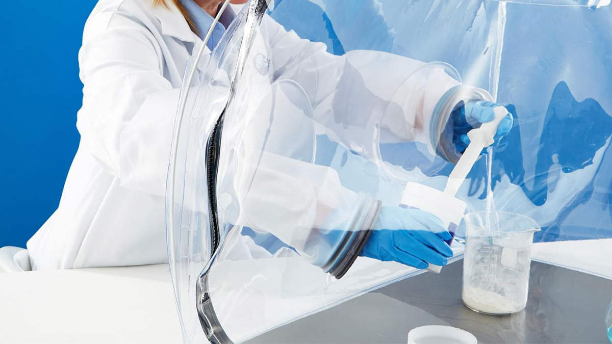 Biomanufacturing professional wearing gloves works in a pop-up benchtop isolator